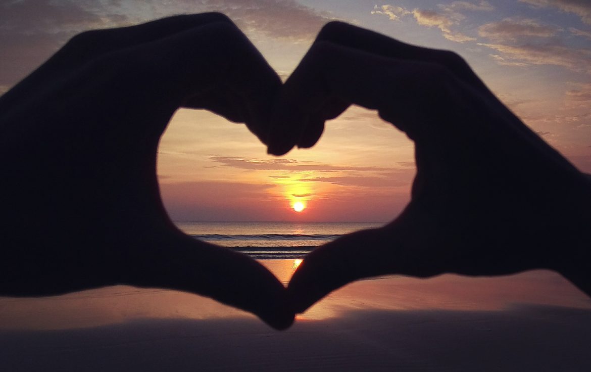 Wir bilden ein Herz mit unseren Händen und rahmen damit den Sonnenuntergang ein.