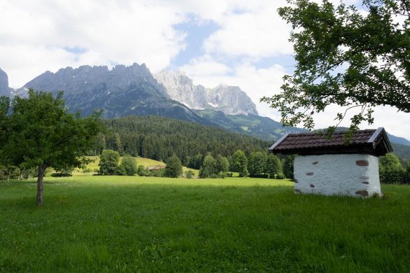 Ein Backofen, der auf der Wiese vor einem Bauernhof steht, mit den Bergen von Tirol im Hintergrund.