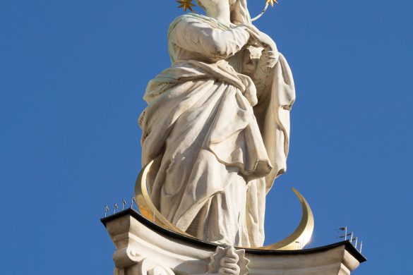 Eine Statue mit einem Heiligenschein voller Sterne vor einem strahlenden, blauen Himmel.