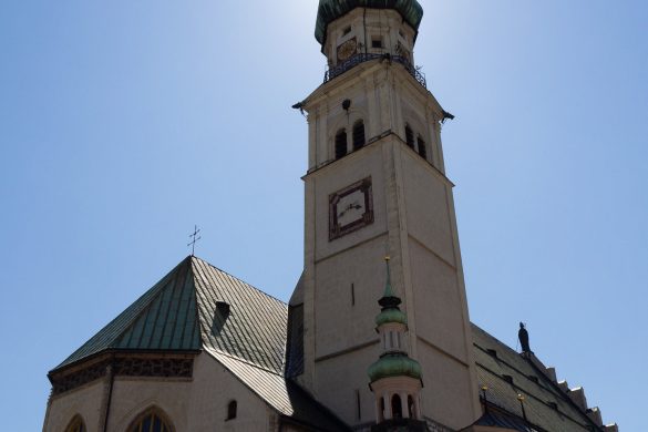 Die Kirch von Hall in Tirol erleuchtet durch die Sonne hinter dem Kirchturm.