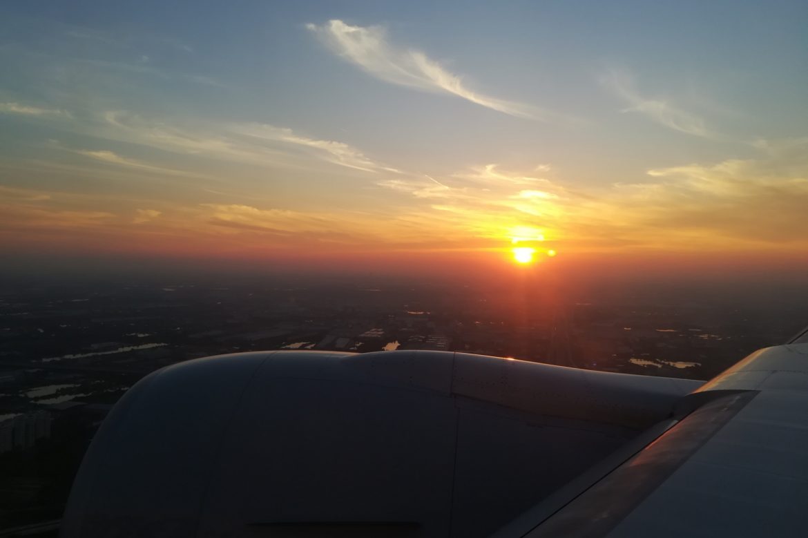 Aus dem Flugzeug beobachten wir, wie sich die Sonne hinter dem Horizont erhebt und den Himmel rot färbt.